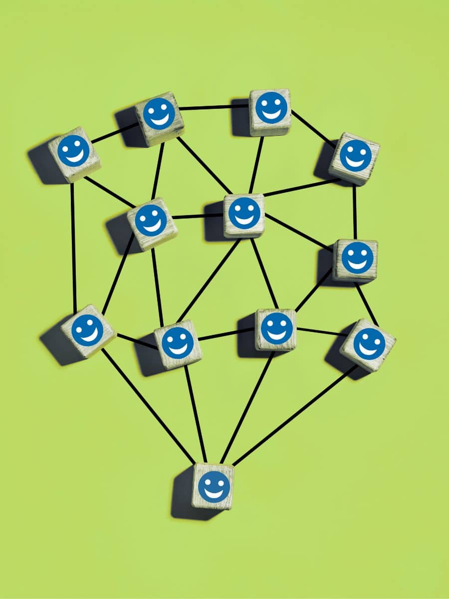 small wooden blocks with blue happy faces on them, connected through a web of lines, on a lime green background
