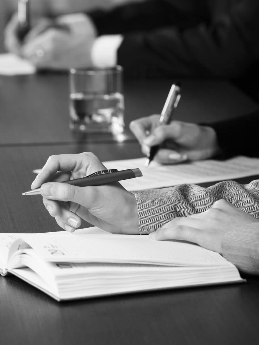 black and white; hands writing in a book